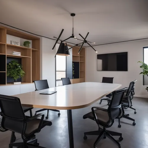 meeting room with white stucco walls and microcement flooring, with a table with a black lacquered top and dark wooden legs in the center, eight chairs with wheels with metal structure and seat and ba