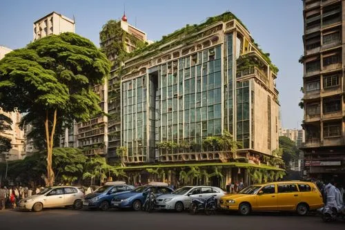 Modern Mumbai skyscraper, sleek glass façade, intricate Indian-inspired carvings, grand entrance with ornate wooden doors, lush green rooftop garden, vibrant street food stalls at base, bustling city 