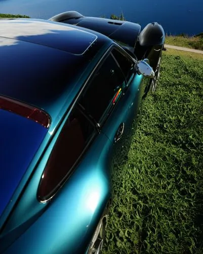 饱满的曲面，高级感，真实,a blue car is parked on the grass next to the water,tail fins,tailfin,targa,wing blue color,pininfarina,ghia,Photography,General,Realistic