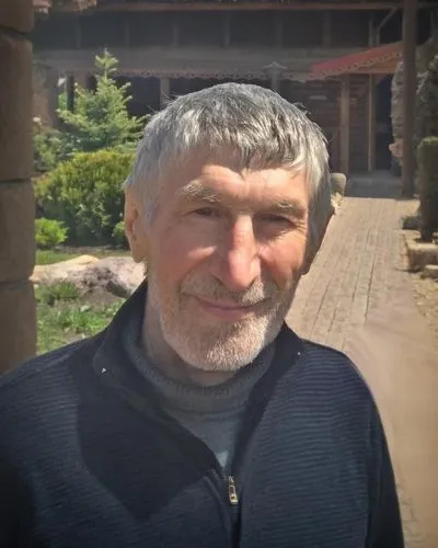 a man is standing by a stone house,kudayev,ivanchuk,zahidov,movsayev,nekliayev,sokurov,tashiyev,khudoberdyev,kulayev,basayev,atsayev,yarkovsky,deukmejian,akhmadov,aripgadjiev,tanayev,abubakarov,hayrap