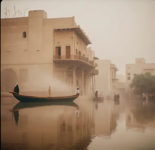 Traditional iraqi style building facing big canel.  Native small boats sailing in canel. Padestrains with arabic clothes. Dairy pulms in the background,jaisalmer,baghdad,dubai creek,iraq,nile river,hu