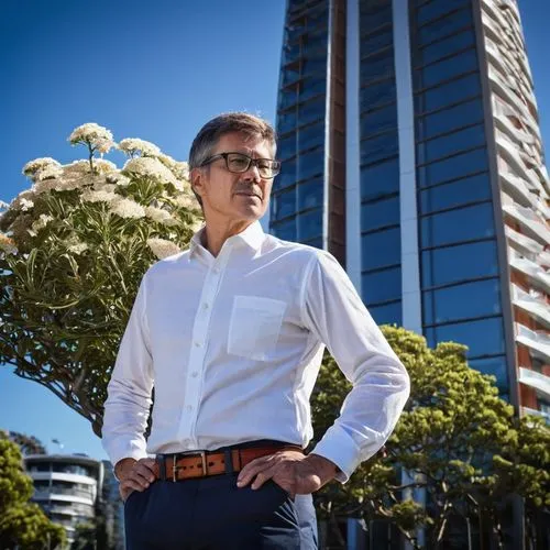 Middle-aged, male, architectural designer, Tauranga, standing, confident pose, glasses, short brown hair, casual clothing, white shirt, dark blue pants, brown leather belt, holding a large blueprint, 