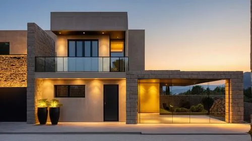 modern house with a store on the ground floor, a large black metal gate on the side. Yellow lights and welcoming colors on the facade. Natural stones make up the facade.,a home that looks to be very m