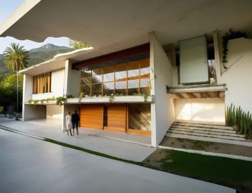 Diseño exterior de una residencia estilo mínimalista, con muros de concreto color blanco, perfiles con canal de acero en losa, ventanal de cristal en la parte superior del acceso, ventana en el estudi