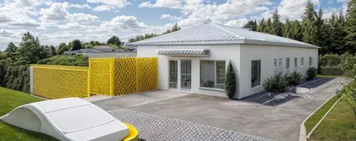 long building with white sloped roof, front bright blue wall and yellow side wall. attached building 2 feet lower with white sloped roof, with cages vertical bars for dogs, green grass around, concret