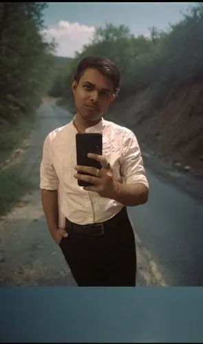 man standing in a road holding a phone with an armband on,khiladi,rajiv,rajesh,deewana,vadra,baazigar