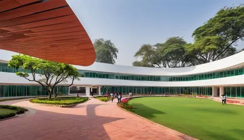 Delhi School of Architecture & Design, modern academic building, white exterior walls, large glass windows, angular roof structure, lush greenery surrounding campus, tropical trees providing shade, st