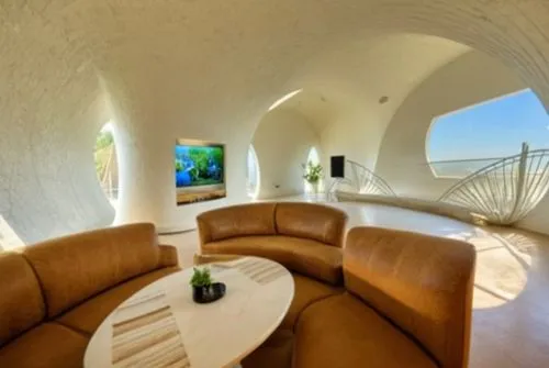 Temporary ecological residence project inspired by snail form
The space inside the residence,a living room with a large white and brown couch,superadobe,vaulted ceiling,earthship,vaulted cellar,dunes 