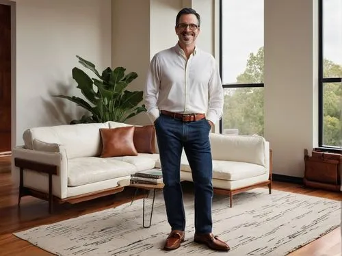 Randy Heller, mature designer, 40s, short black hair, glasses, facial stubble, white shirt, dark blue jeans, leather belt, brown loafers, standing, leaning against, modern minimalist interior, wooden 