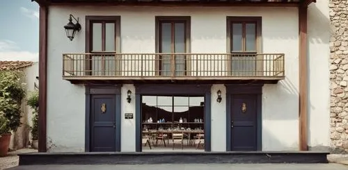 - Uso misto com bar embaixo, e mesas de esplanada.
- Portas de madeira cor grená e paredes brancas e molduras cinzas. 
- Inserir toldo de lona "listrados cor azul e branco".
,a building with windows a