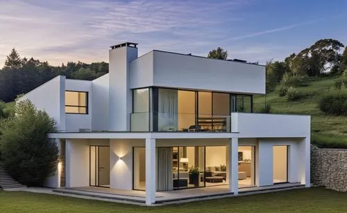 A modern, minimalist white house with clean lines and a few stone accents on the façade. The porch features white beams, complementing the sleek, minimalist design. The house is slightly elevated abov