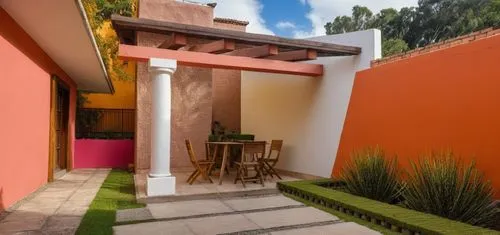 REMODELACION DE UNA CASA CON ESTILO MEXICANO, USO DE COLORES VIVOS, MADERA, PISOS DE BARRO, FLORES Y UN ESPEJO DE AGUA CON FUENTE EN UN MURO,the backyard of a residence with a table and chairs next to