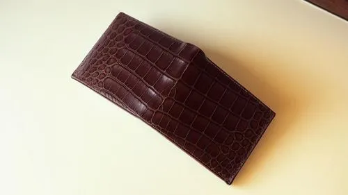 an alligator skin wallet is seen laying on the table,block chocolate,chocolate bar,pieces chocolate,chocolate bars,ganache,swiss chocolate