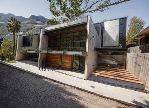 DISEÑO EXTERIOR DE UNA CASA RESIDENCIAL ESTILO MINIMALISTA, CON UN VENTANAL DE CRISTAL  EN EL AREA DE ACCESO PRINCIPAL, CANALES DE ACERO EN LA LOSA, ELMENTOS DE MADERA, MUROS COLOR BLANCO, COLORES NEU