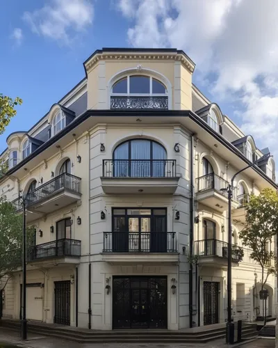 a Renaissance building with a sandstone base and the upper floors in white plaster, with several worked frames, the windows on the upper floors have a balcony in front with black iron railings, the wi