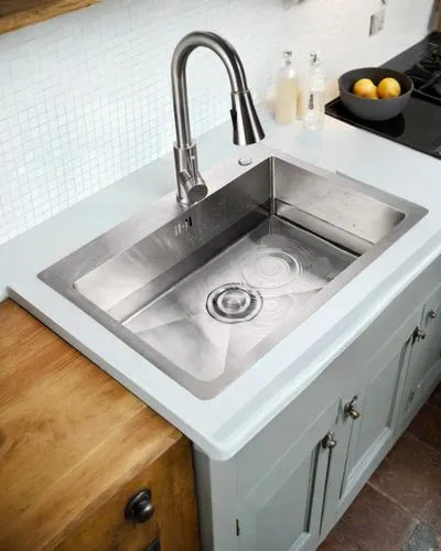 a kitchen sink under a counter with a towel and oranges,kitchen sink,whirlpool pattern,mixer tap,bathroom sink,stone sink,sink