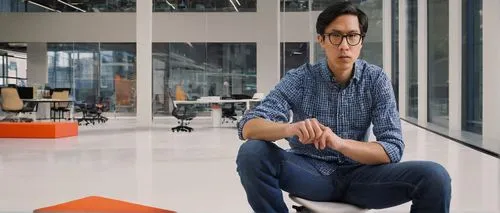 Modern digital designer, male, 30s, bespectacled, short black hair, white shirt, dark blue jeans, sneakers, sitting, Amazon headquarters, Seattle, USA, glass building, minimalist interior, whiteboards