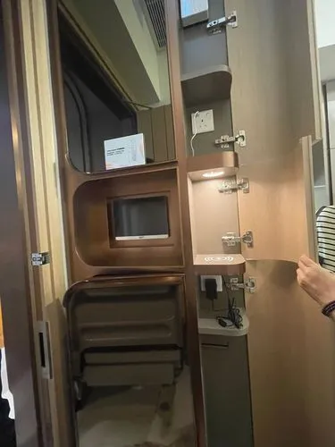 a person standing inside of a brown trailer next to doors,roomette,train compartment,unit compartment car,motorhome,travel trailer,christmas travel trailer