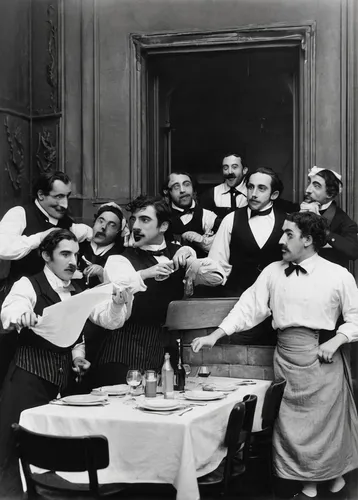 Devise a comedic musical set in a bustling restaurant where waiters and kitchen staff break into song and dance to save the day.,apéritif,dinner party,toasts,vaudeville,a party,toasting,drinking party