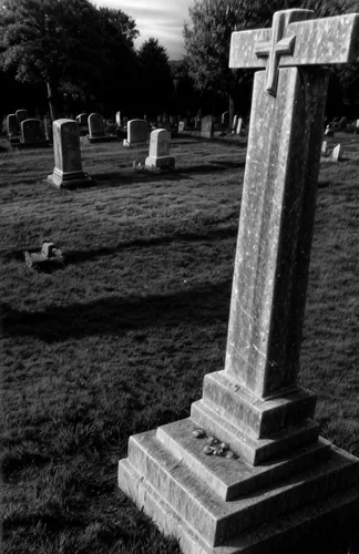 A creepy, spooky ancient cemetery at twilight, a ghostly figure is seen amongst the weathered tombstones. Infra-red style.,grave stones,memorial cross,central cemetery,burial ground,grave arrangement,