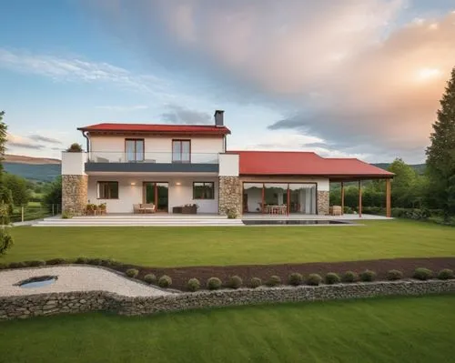 A minimalist house with a gable red roof, featuring stone accents on the facade, set in a village surrounded by small hills and forest. The large windows have anthracite gray frames, adding a sleek, m