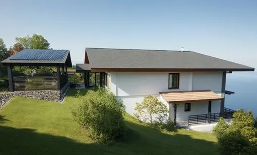 small modern house. The walls are white. Gray roof. There is a forest around the house.,two houses on a hill next to a body of water,electrohome,holiday villa,passivhaus,esalen,glickenhaus,solar photo