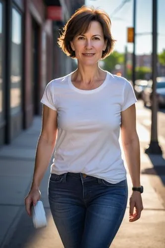 Mature lady, 35yo, strong facial features, short brown hair, minimal makeup, casual wear, jeans, white T-shirt, sneakers, standing, urban environment, city streets, morning time, sunny weather, shadow