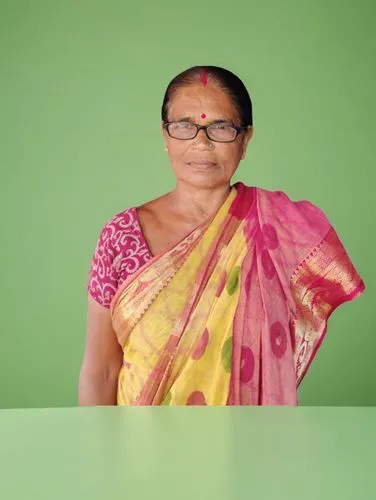 a woman in a colorful sari with glasses sitting at a table,sivakami,pramila,suseela,shailaja,rajeswari,vasanthi