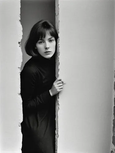 Beautiful woman enters the room through a narrow gap in the wall.,the woman is hiding behind the  in a wall,moskvina,kieslowski,ronstadt,varda,audrey hepburn,mathilda,Photography,Black and white photo