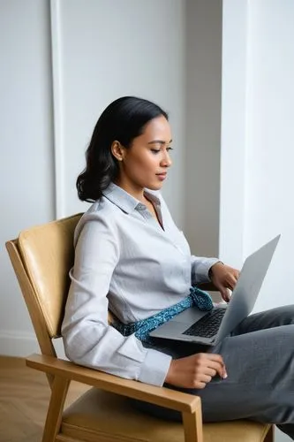 woman using a laptop computer sitting on a chair,woman sitting,distance learning,telepsychiatry,telecommuting,telecommuter,girl sitting