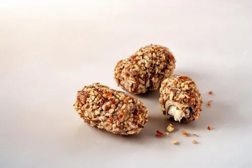 three nut covered pieces of chocolate on white table,oatmeal balls,energy balls,sesame candy,almond nuts,coconut balls,laddu,Small Objects,Indoor,Rustic Cabin