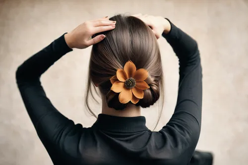 beautiful, young girl from the back. she straightens her hair. she is styling her hair. she decorates her hair with a flower. she has long, beautiful, thin fingers. she ran her fingers through her hai