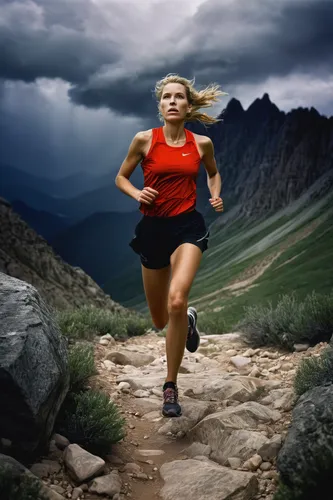 Under a stormy sky, a fearless female runner embraces the challenge of a rugged mountain trail.,run uphill,middle-distance running,female runner,long-distance running,ultramarathon,trail running,endur