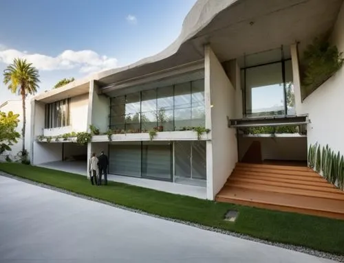 Diseño exterior de una residencia estilo mínimalista, con muros de concreto color blanco, perfiles con canal de acero en losa, ventanal de cristal en la parte superior del acceso, ventana en el estudi