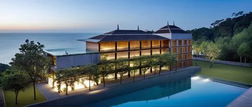 an art - deco house sits atop the hill above a large body of water,lefay,amanresorts,holiday villa,beach house,uluwatu,esalen,pool house,beachhouse,house by the water,luxury property,anantara,dunes ho