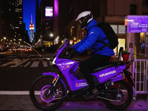 A Grubhub delivery driver rides near the Empire State Building lit up in purple in honor of World Cancer Day on February 04, 2021 in New York City.,electric scooter,yamaha,courier driver,purple,yamaha