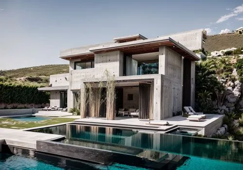 A cinematic photo of a luxurious modern architectural villa with an indoor/outdoor illuminated pool, rock walls with a waterfall from above, minimal, elegant, grey Concrete walls, rammed earth walls, 