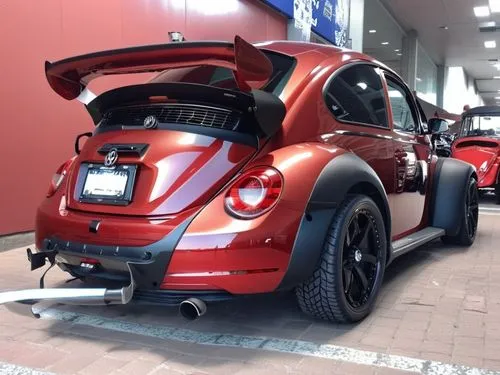 VW Beetle California style, bright red metallic, tinted windows, with rims, all-terrain tires and large fenders, a large F1-style rear spoiler, matte black bumpers,there is a very cool colored car par