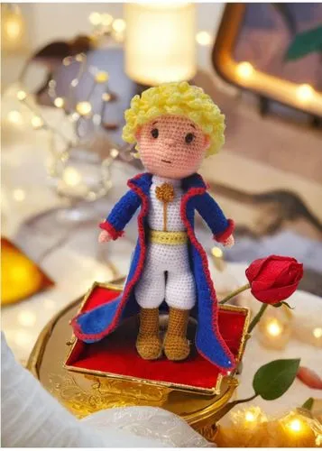 a crocheted doll in a costume on a red and gold plate,enjolras,angel gingerbread,marzipan figures,thorfinnur,brandybuck,frigga