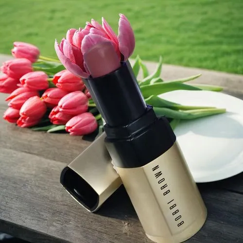 a small lipstick and pink flowers sitting next to plates,tuberose,nars,guerlain,cream blush,rossetto,natural cosmetic,Small Objects,Outdoor,Tulips