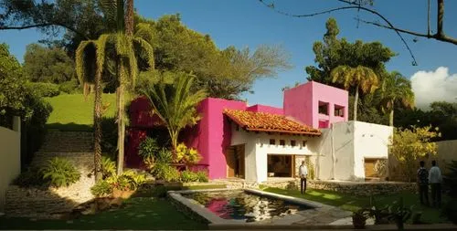 EL EXTERIOR DE UNA CASA CON ESTILO MEXCANO MODERNO, USO DE COLORES VIBRANTES, MATERIALES REFIONALES, TEJA, VIGAS DE MADERA, EN UN AMBIENTE EXUBERANTE, ESTANQUE DE AGUA AL FRENTE.,a colorful house and 