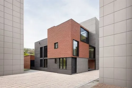 The modern brown brick house features a minimalist style with a dark gray painted ground floor and back. Located in an urban area, the design includes large windows for natural light. The materials us