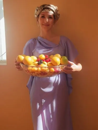 My beautiful hostess came towards me with a bowl of the most delicious fruit and beamed at me with love.,a woman in purple standing against a yellow wall with a plate of fruit,loquat,apricot preserves