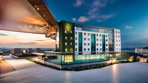 The hotel is a modern, multi-story building with a sleek, contemporary design. The exterior combines light-colored walls with dark brick corner and features large windows that allow natural light to f