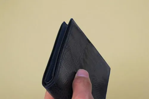 a hand holding a wallet on a white surface,wallet,pocket flap,origami paper plane,mortarboards,pocket tool,wallets