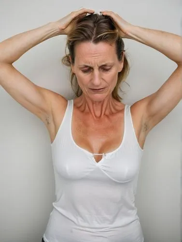 a German 40-y-o woman holding her head with a white top,a woman in white top holding her hands on her head,menopause,premenopausal,shoulder pain,pranayama,cardiac massage,torticollis