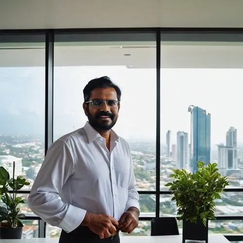 Middle-aged male architect, Sri Lankan, matured facial features, glasses, black hair, beard, white shirt, black trousers, leather belt, holding blueprints, standing, modern architecture office, Colomb