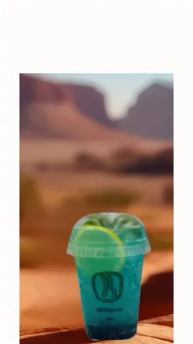 there is a plastic cup with a green apple in it,green icecream skull,desert background,water cup,daiquiri,desert,semidesert