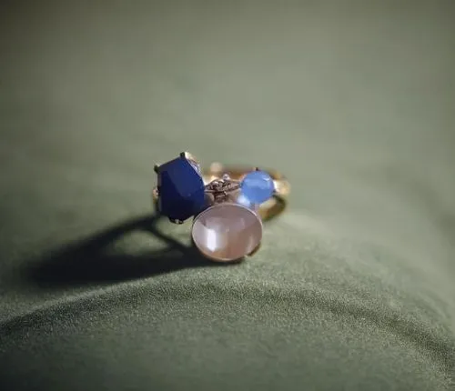 two colored stones sit on the fabric,anello,chalcedony,birthstone,opaline,boucheron,agta