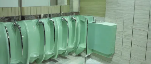 Describe a clean urinal in a modern hotel restroom.,urinal,bathroom accessory,shower bar,washroom,toilets,soap dispenser,toilet,shower door,public restroom,bathroom,douhua,shower base,wash hands,toile